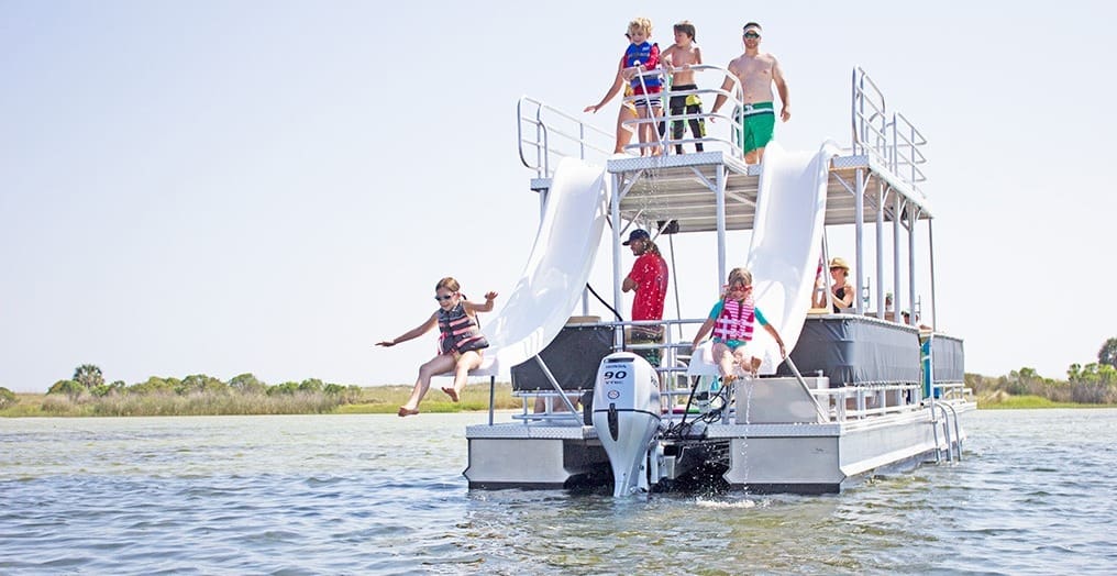 Image of kids going down the slides off of a double decker pontoon boat.