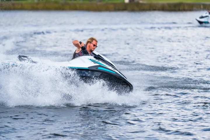 Person riding a jet ski on a lake, creating splashes.