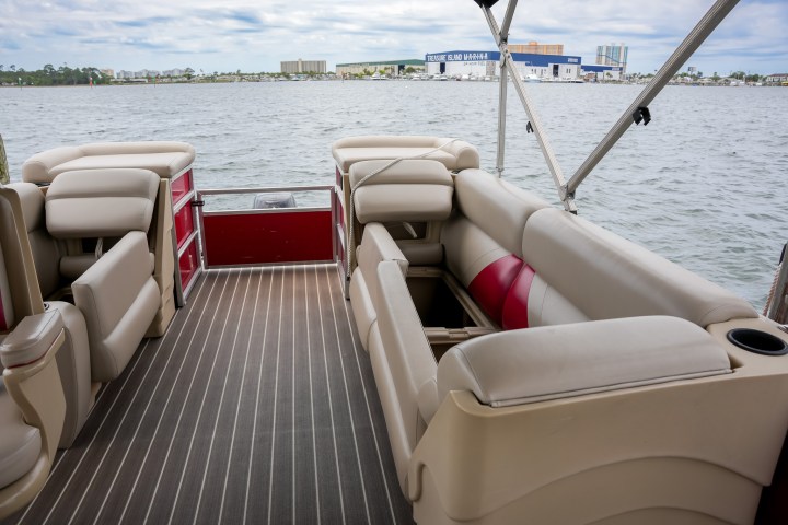 Interior of a boat with beige seating and a view of the water and distant buildings.