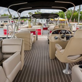 Interior of an empty pontoon boat with beige seats and driver's console.