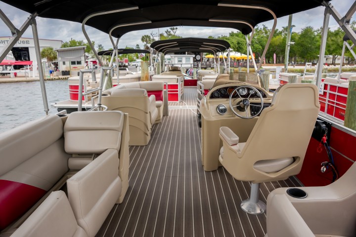 Interior of an empty pontoon boat with beige seats and driver's console.