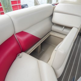Boat seating with storage compartment open on wood flooring.