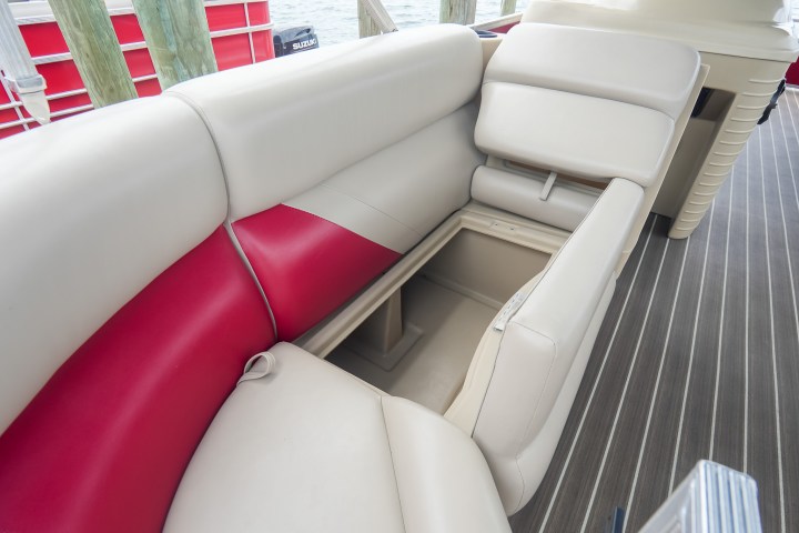 Boat seating with storage compartment open on wood flooring.