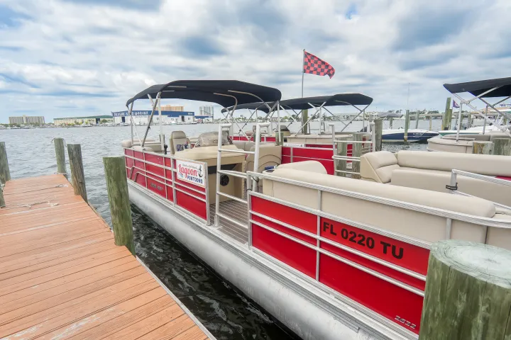 Red pontoon boat docked on a wooden pier with a checkered flag.