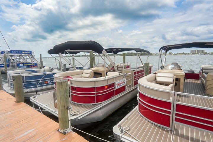 Pontoon boats docked at a marina under a cloudy sky.
