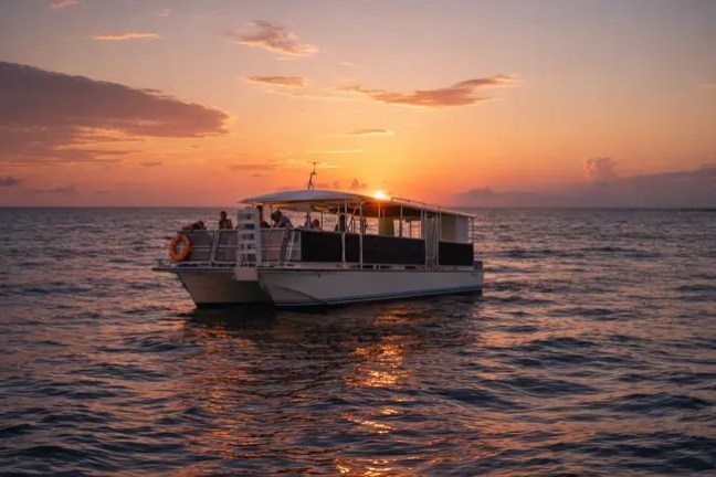 Boat with people on a calm sea at sunset.