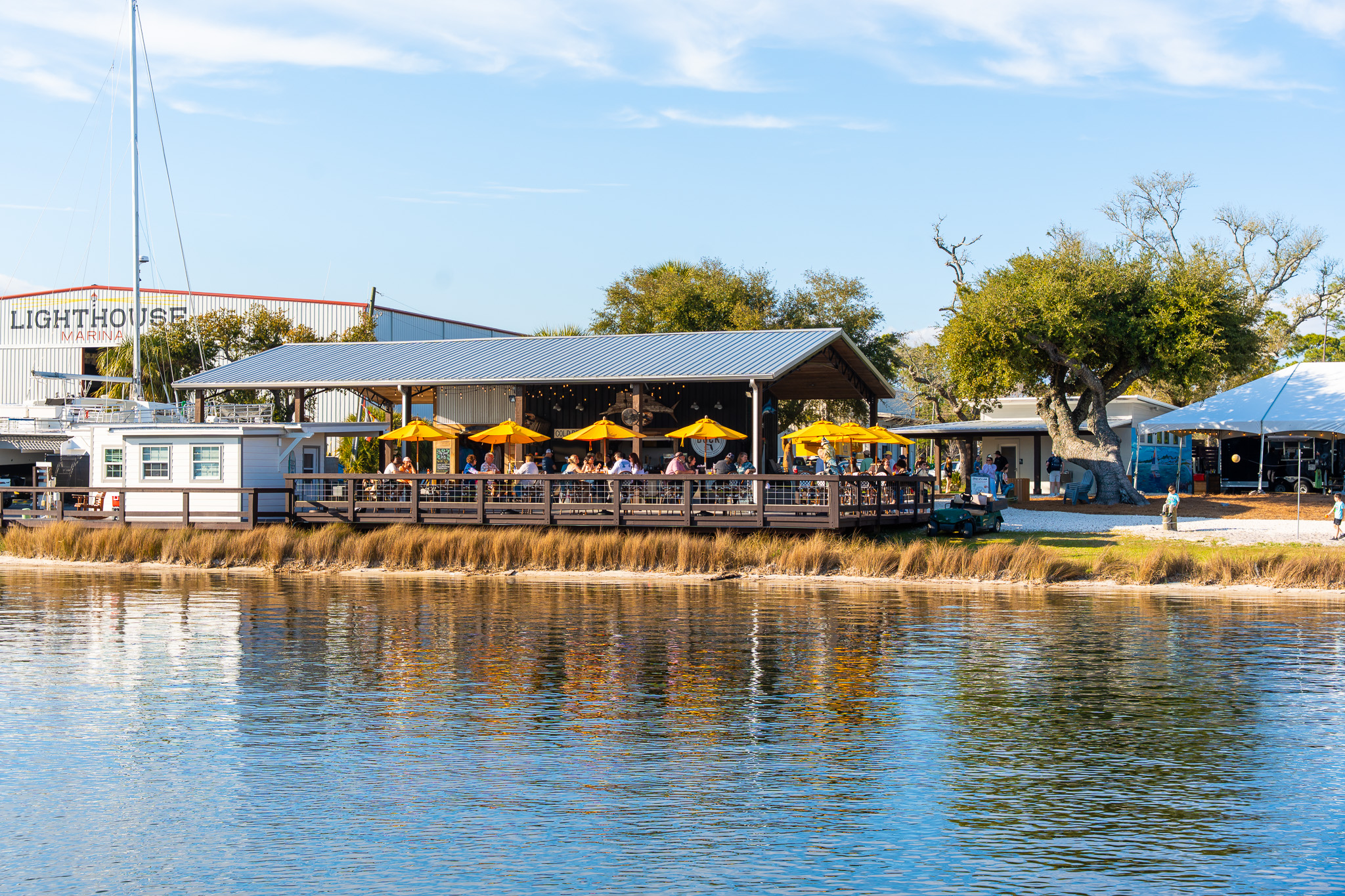 Outdoor restaurant with yellow umbrellas by a waterfront.