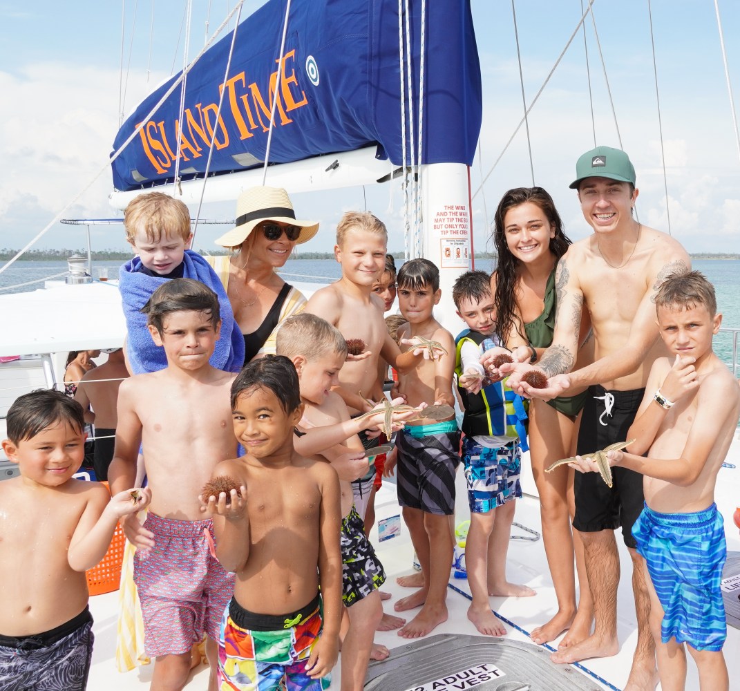 Group of children and adults smiling on a sailboat.